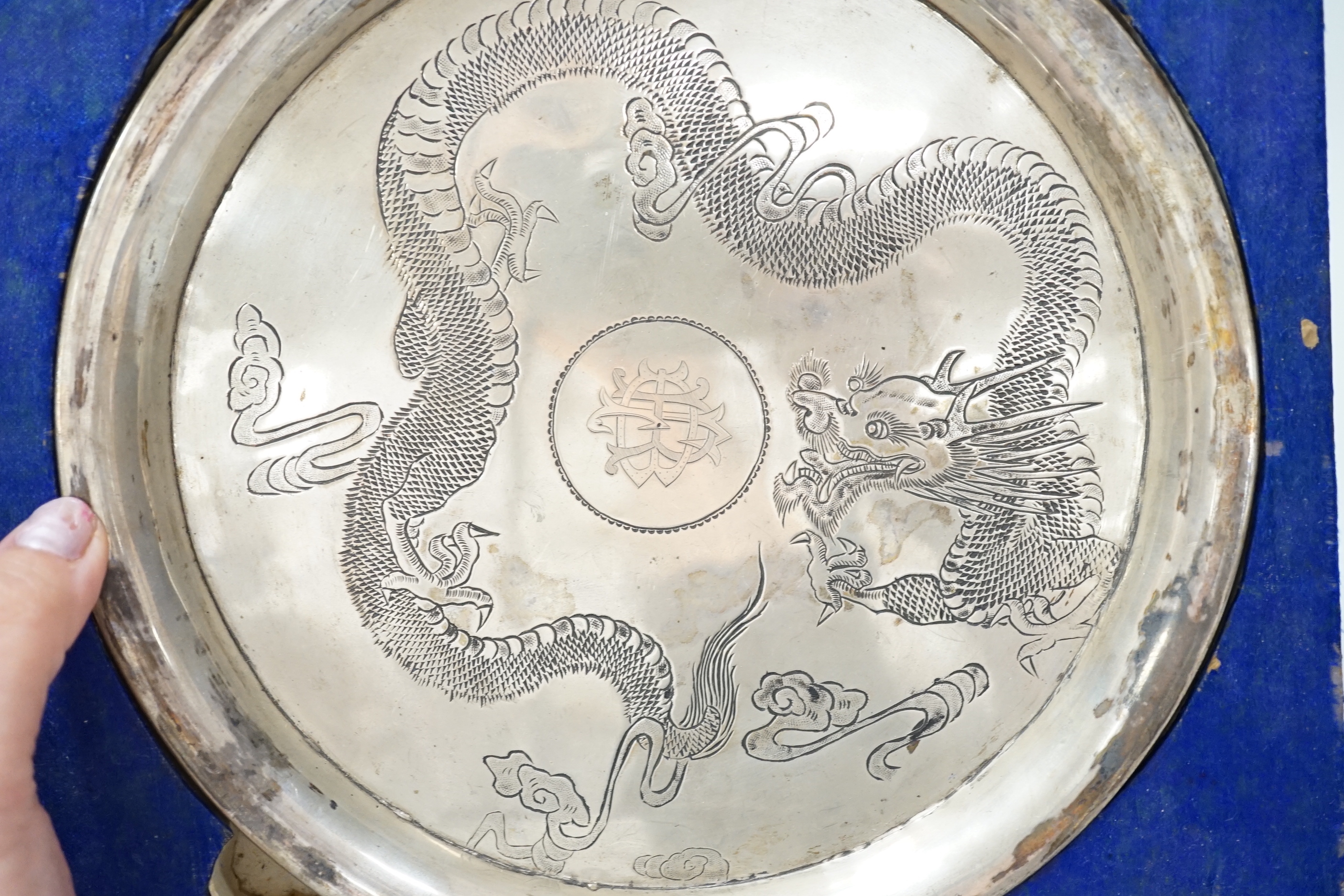 A Chinese white metal ‘dragon’ salver, late 19th century, 20.2cm carded silk box base and two similar napkin rings.